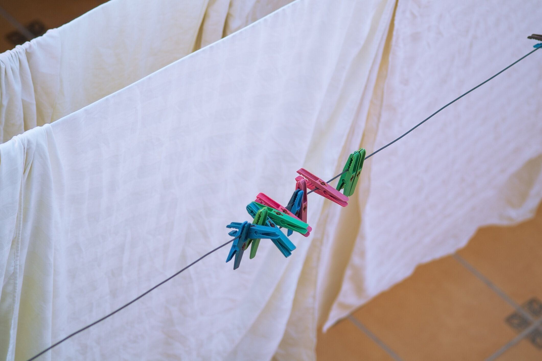 洗濯後のカラフルな衣類は、風で乾かすために物干し竿、ベッドリネン、シーツ、タオルに吊るされます。家庭用衛生用品