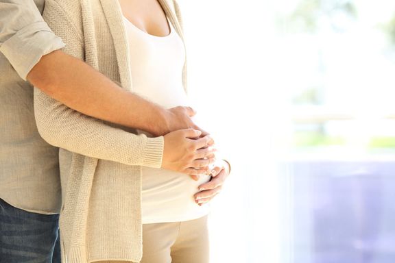 妊娠中の腹に触れる親の手のクローズ アップ