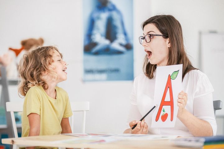 言語聴覚士 ' 絵手紙と小道具を使用して正しい発音で子供と作業します。