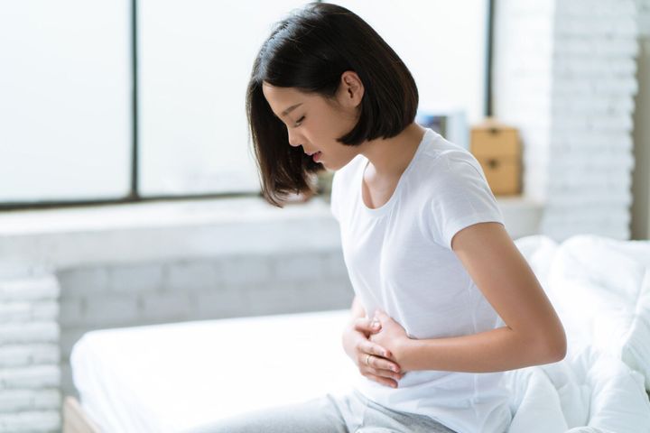 アジアの女性が彼女の胃の痛みハード彼女は目覚める夜中彼女が眠る間。