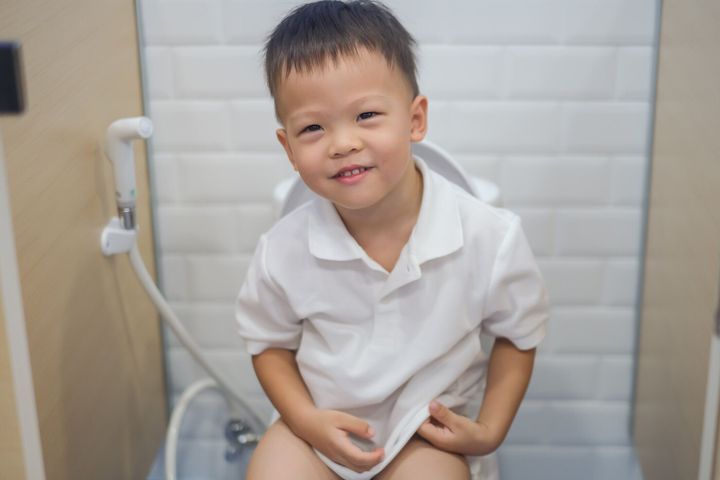 アジアの 2-3 歳の幼児男の子の子供は、トイレの近代的なスタイルに座って、小さな男の子は子供のための公共/学校のトイレを使用します