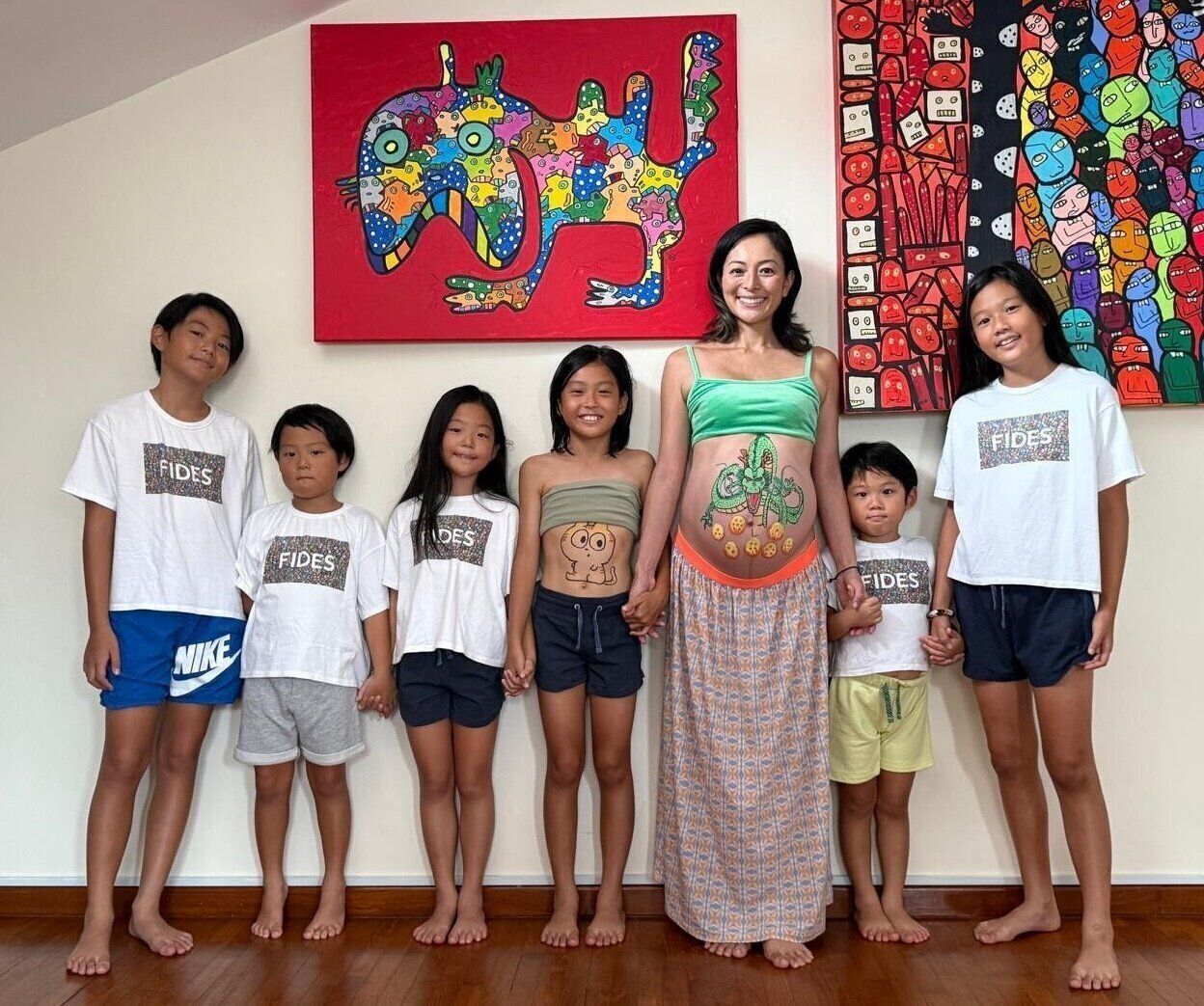 第7子を妊娠中の日記さんと、6人の子どもたち。日記さんのアート作品の前で。