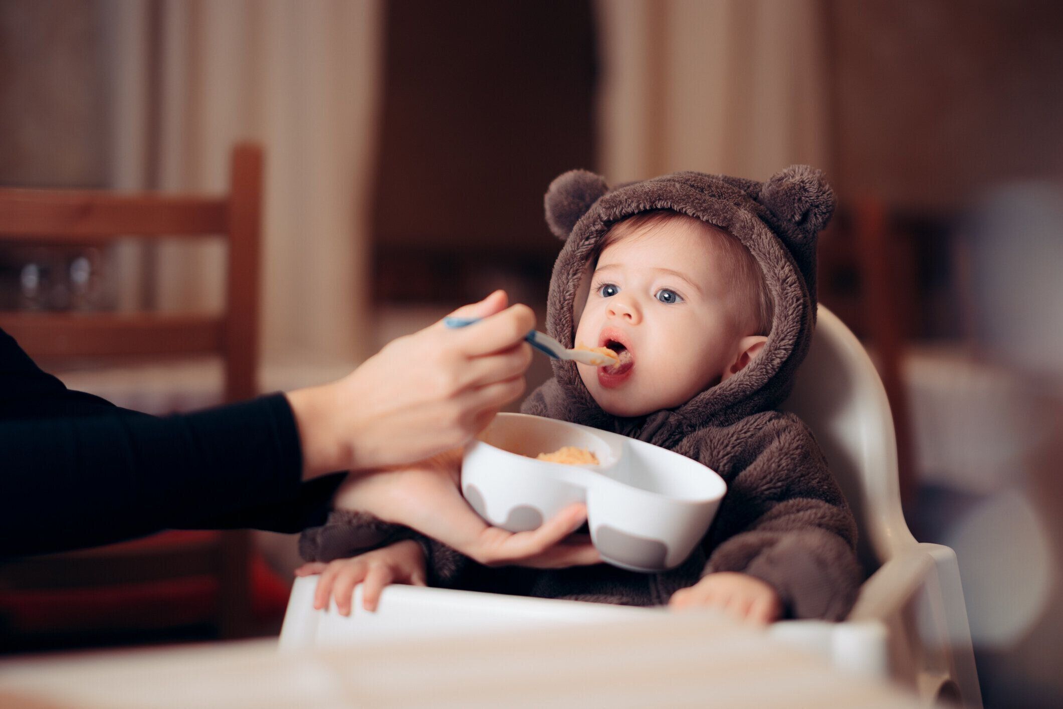 レストランの椅子に座って健康的な食べ物で食べる赤ちゃん