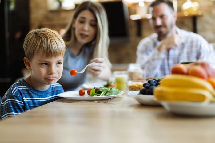 野菜を食べることを拒否する不幸な小さな男の子