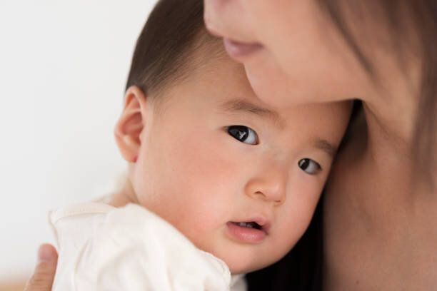 彼の母親に抱きしめられた0歳の赤ちゃん