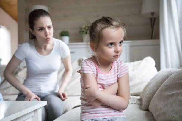 怒った母親が少し悲しい幼児の娘を叱る
