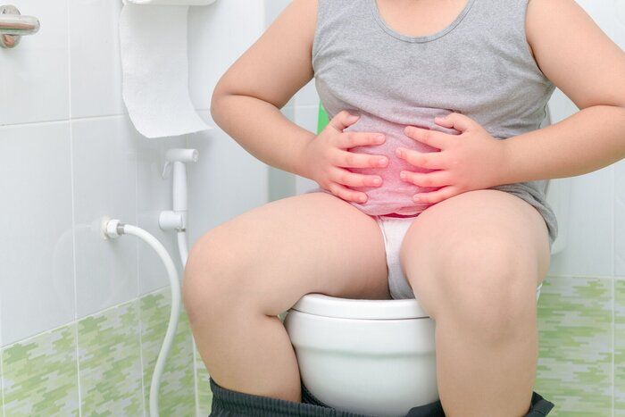 少年の胃に苦しむし、トイレに座っている下痢