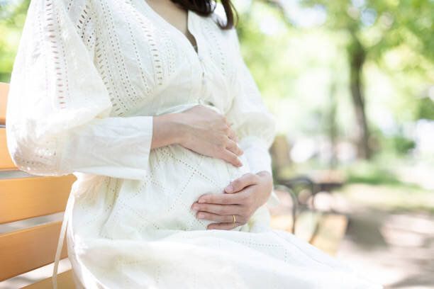 公園のベンチに座っている妊娠中の女性