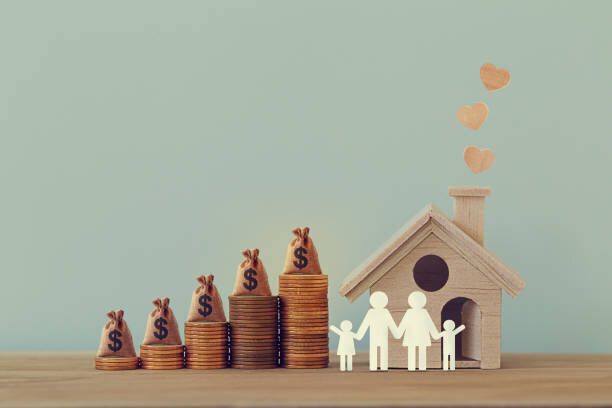 ミニハウスとハート、家族、テーブルの上に上昇コインの列に米国のお金袋。家族税の給付、住宅固定資産税の概念:住宅株式ローン、不動産事業投資を描いています。