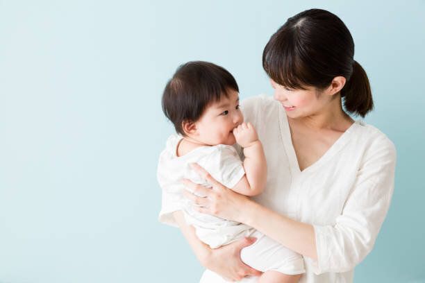 アジアの母と赤ちゃんの青い背景に分離