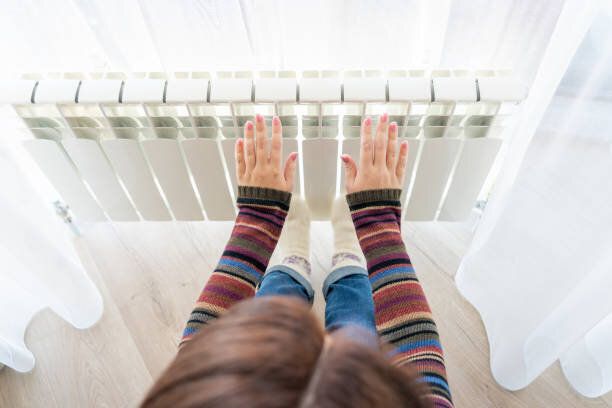 女の子はホットラジエーターの上に凍った手を温め、クローズアップビュー