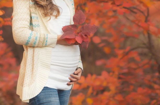 赤秋の公園でウォーキング カジュアルな服装の若い妊婦のポートレート、クローズ アップ