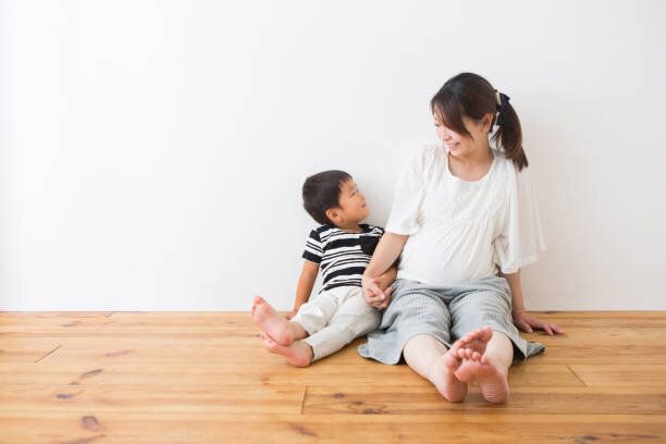 男の子と妊娠中の女性は、床に座っている人
