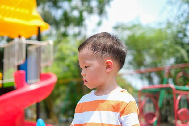 かわいいアジア 2-3 歳の幼児の男の子は楽しい遊んでいる間に発汗、遊び場で屋外運動、熱中ストロークの概念