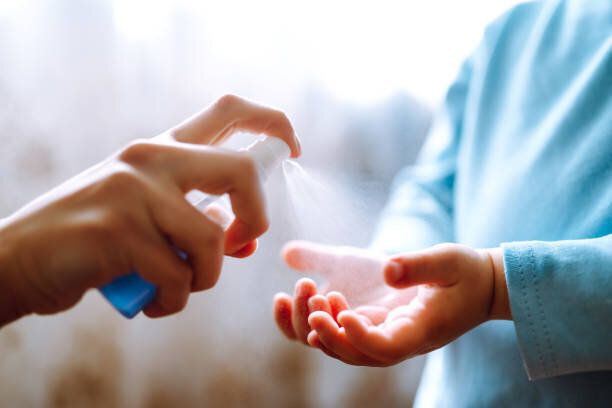 手コロナウイルス保護のために消毒剤を使用する母子。