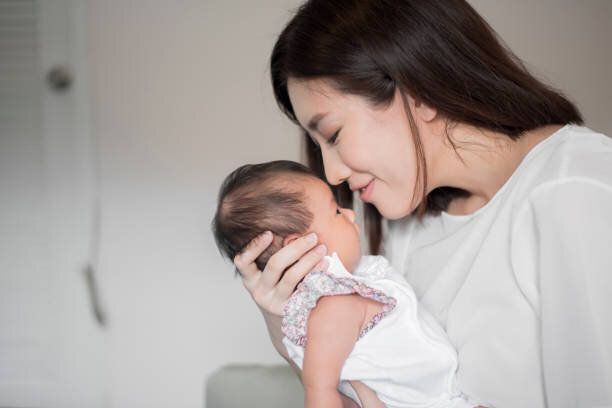 彼女の腕の中に生まれたばかりの赤ちゃんを抱いている美しい女性