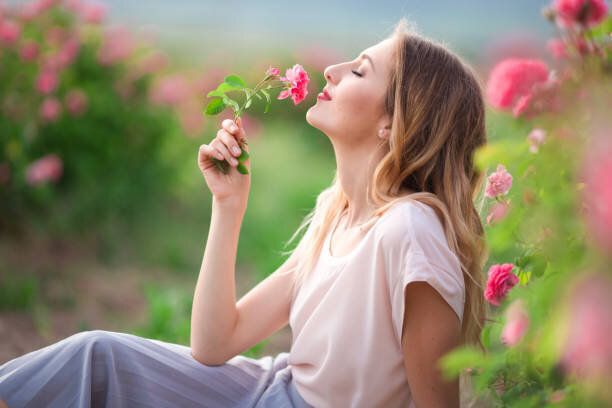 美しい少女は庭にピンクの花バラの残りの部分を持つカジュアルな服を着てください。