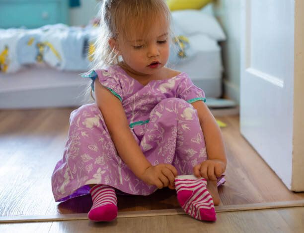 服を着る方法を学ぶ幼児は、外出するために彼女の靴下を履きます。子どもの発達。