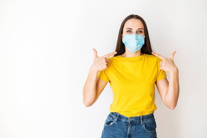 女性は彼女の顔に医療マスクを指し示す