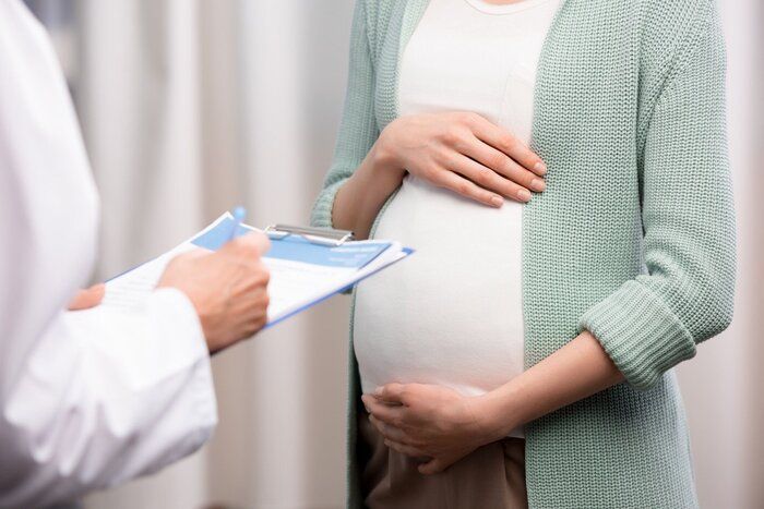 妊娠中の女性の胃を保持しながら書き留めて医師のクロップ撮影