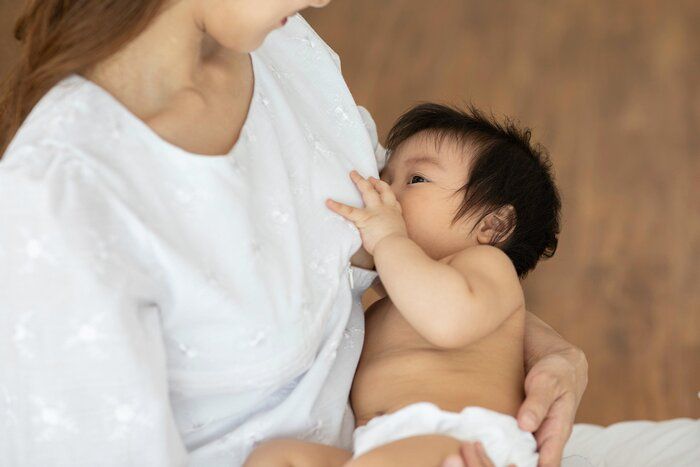 健康な赤ちゃんのための子供の免疫システムを作るための彼女の新生児と自然なママの乳房からの母乳育児を保持する母親, 健康な赤ちゃんの概念, 選択的な焦点