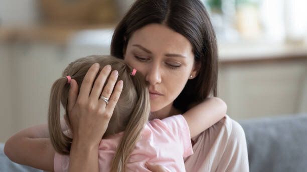 思いやりのある若い母親は、小さな就学前の娘を慰めます。