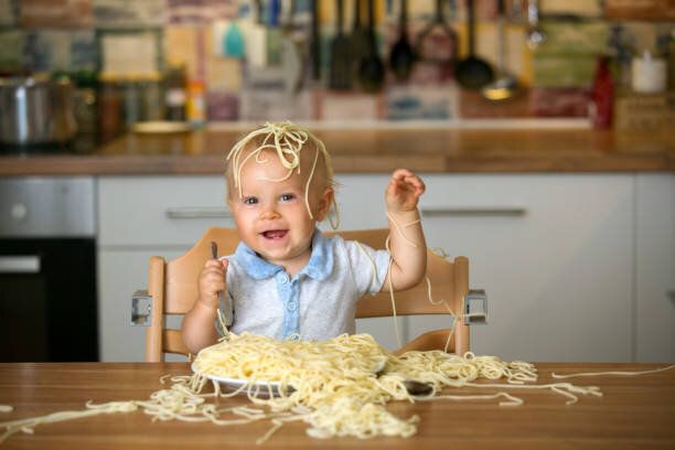 幼児子供、昼食にスパゲッティを食べると混乱を作る小さな男の子