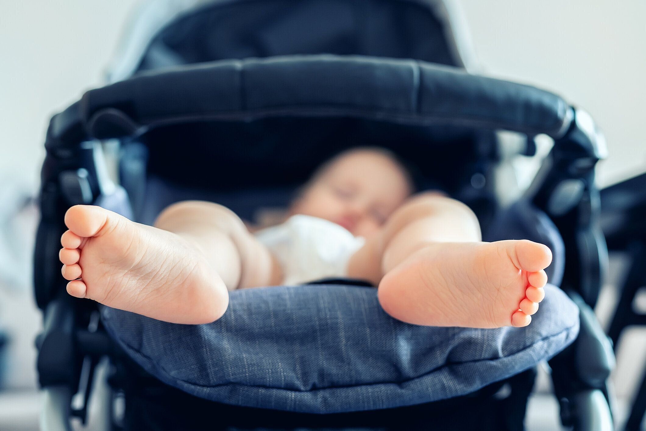 かわいい愛らしい白人のブロンドの幼児は、昼間にベビーカーで眠っています。子供のヘルスケアと幸せな子供時代の概念