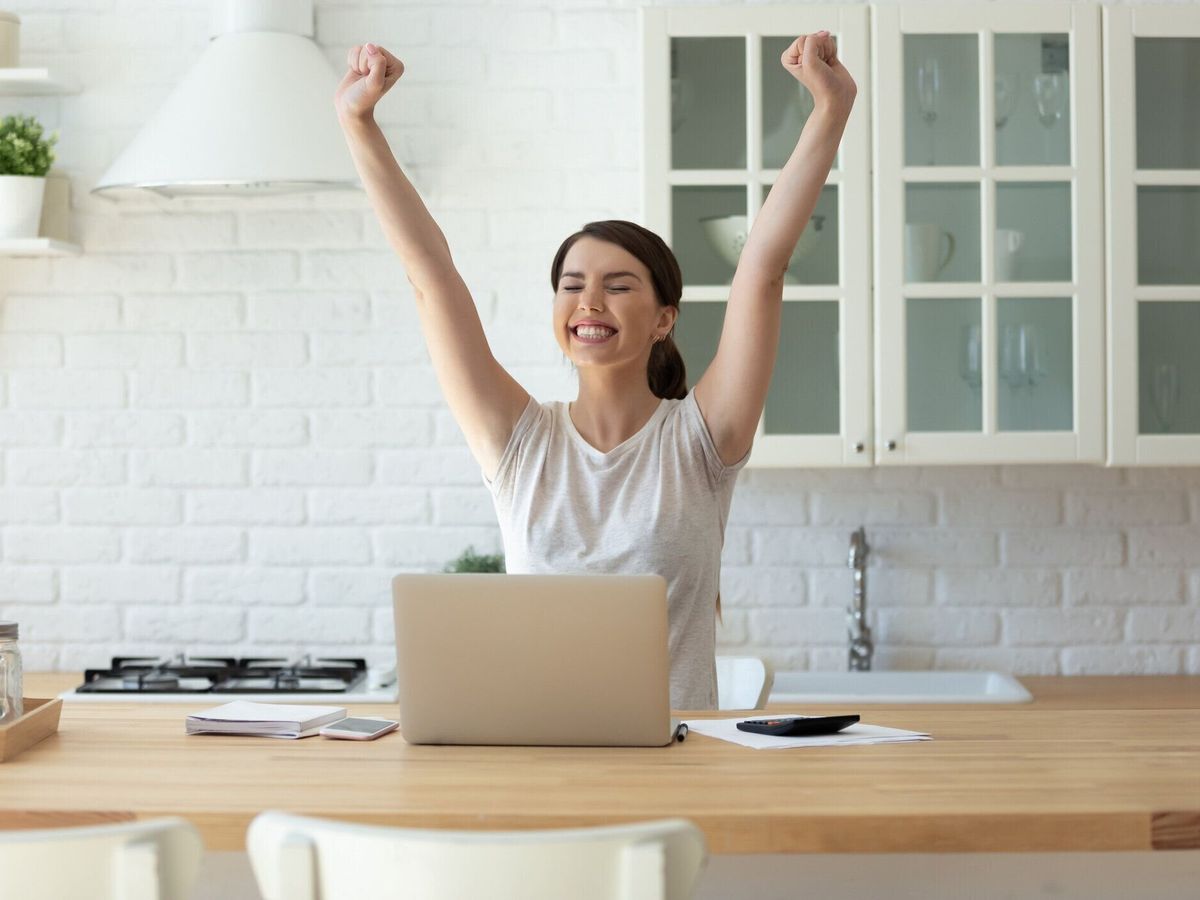 計算のための電卓とラップトップを使用して興奮若い魅力的な女性。