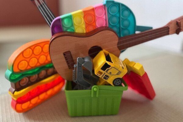 買い物かごから溢れ出すおもちゃ（買い与えすぎたイメージ）
