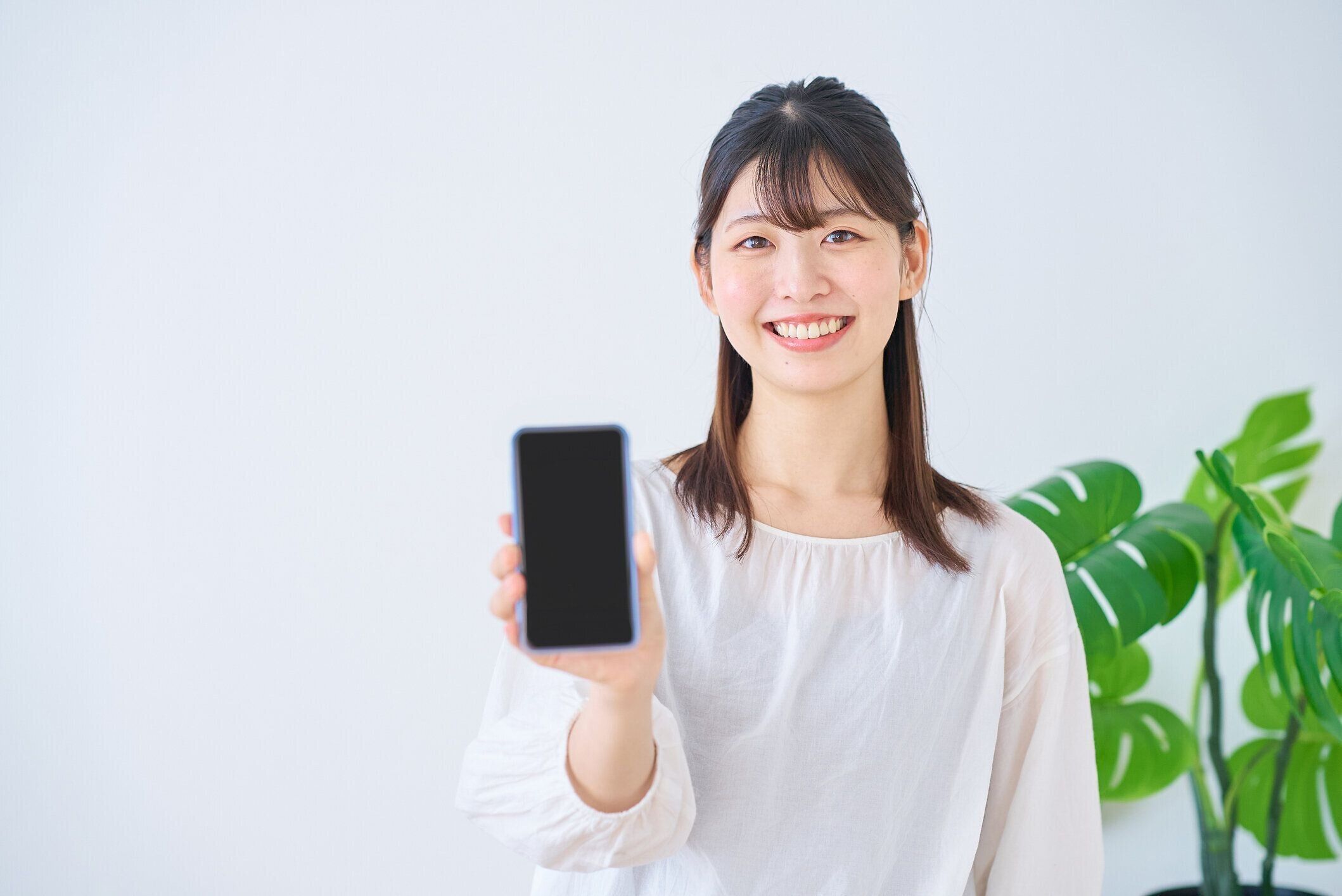 スマートフォンの画面を示す若い女性