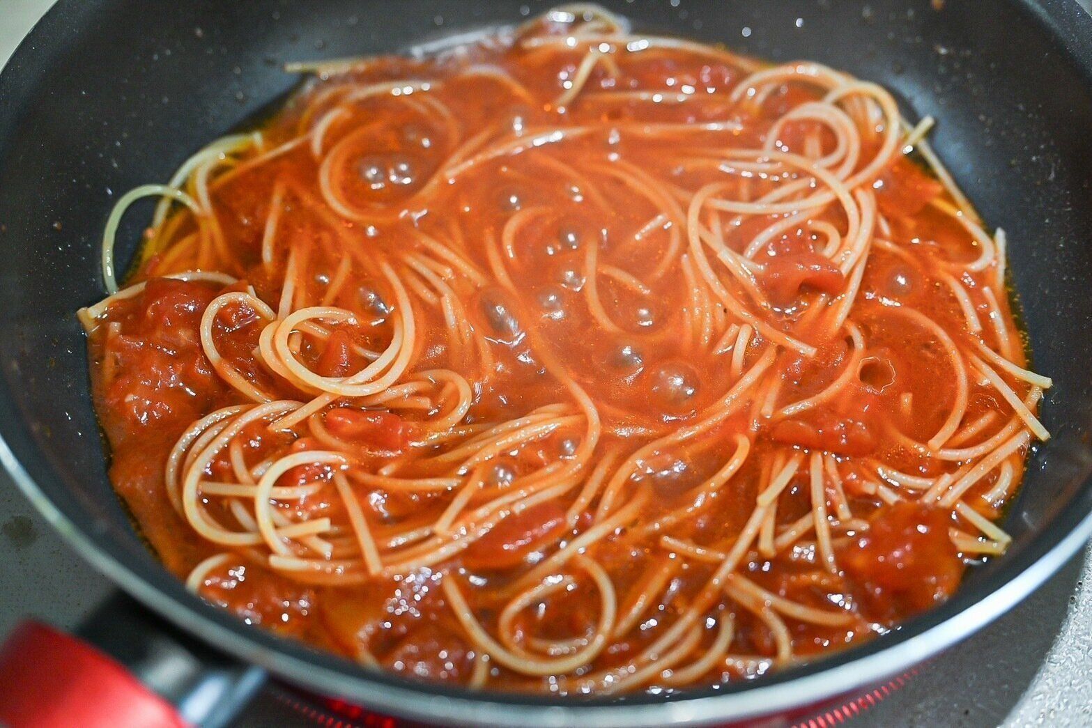 フライパンに入ったトマトソースで煮込んだパスタ
