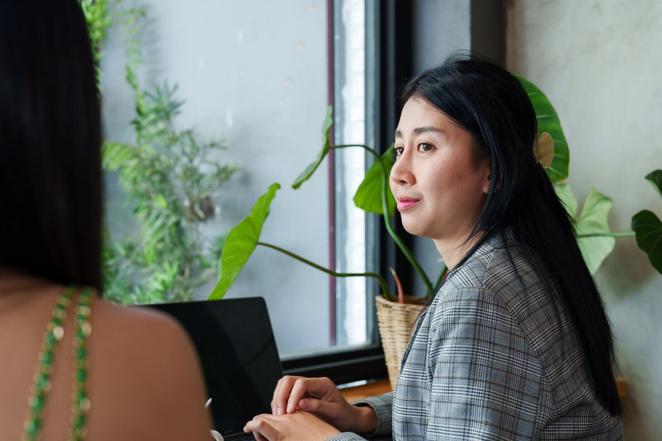 アジアの若い実業家が座って友人とおしゃべりするポートレート。仕事とその隣のラップトップでタイピングについて相談する 外で仕事をしなければならない日には