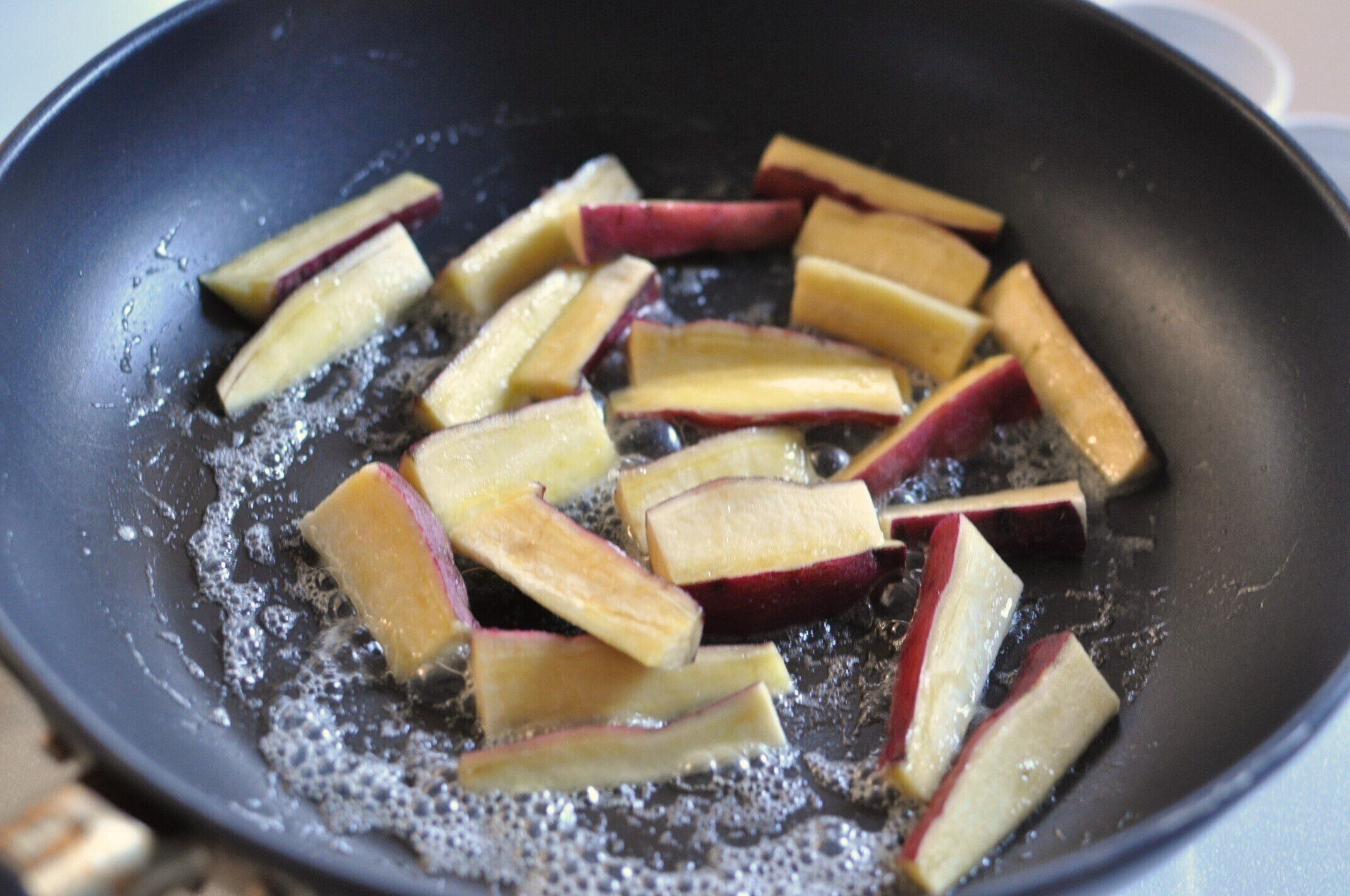 フライパンにさつまいもを加えて、バターを絡める様子