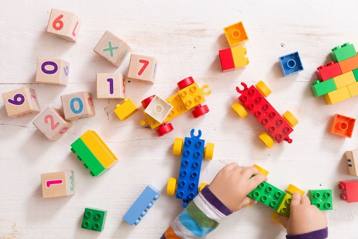 数字と木製白地にカラフルなグッズ レンガと木製キューブと遊ぶ子供。幼児学習番号。おもちゃを取って子供の手。