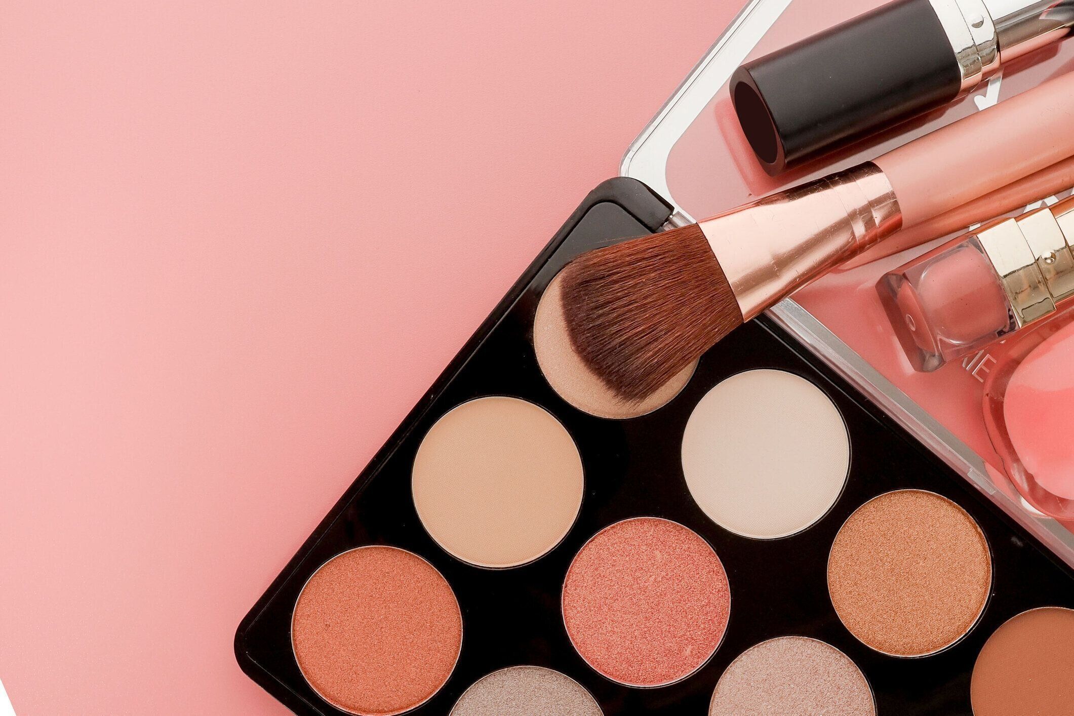 コピースペース付きピンクの背景に様々なメイクアップ製品