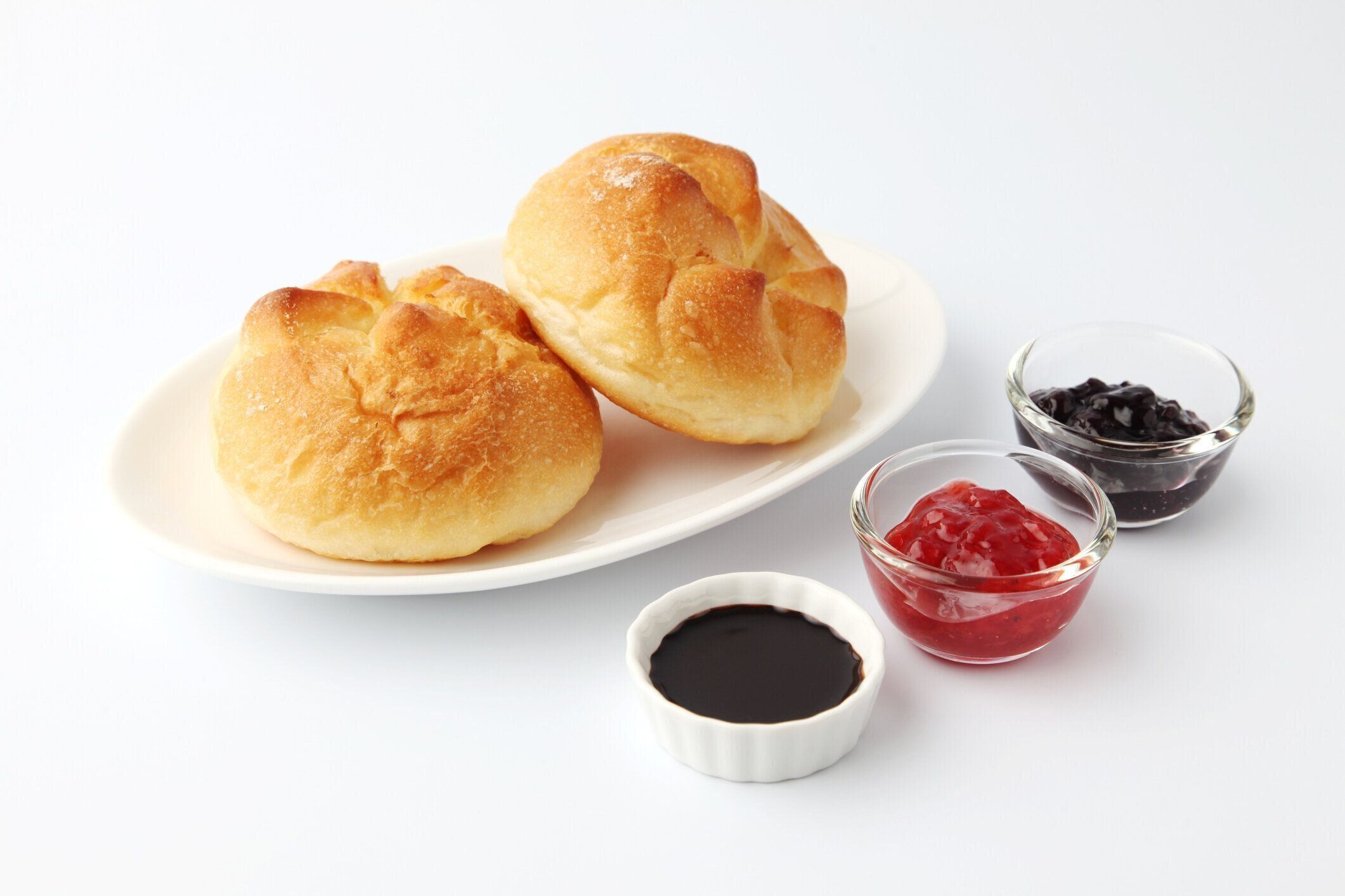 白い背景にイチゴジャムのあるプレートにバターパンロール