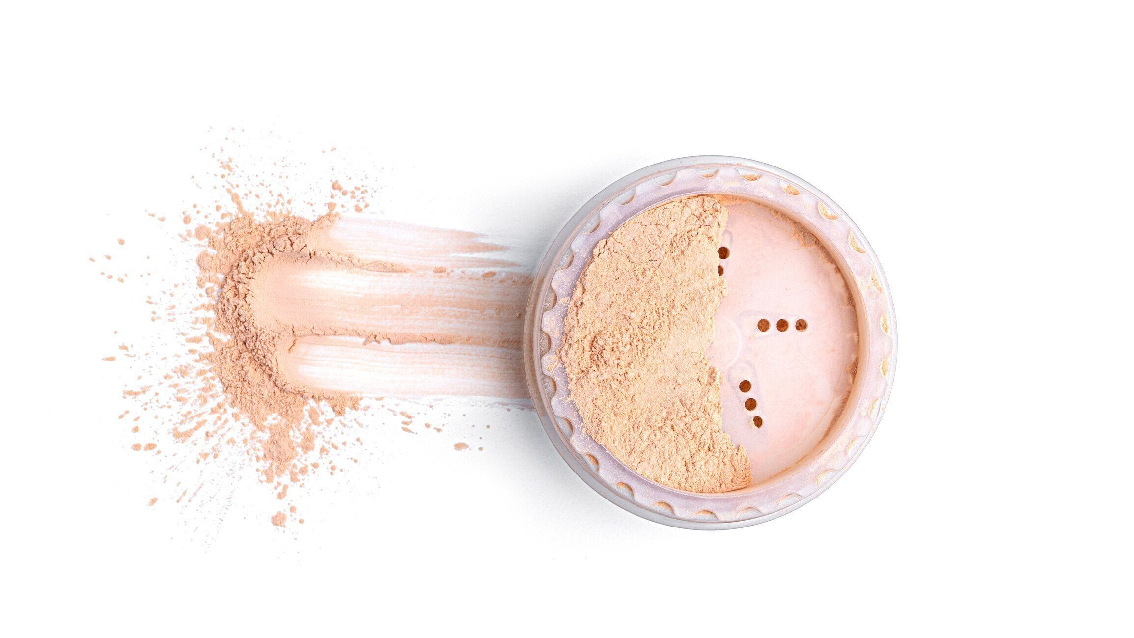 白い背景にゆるい化粧品パウダーを持つ瓶