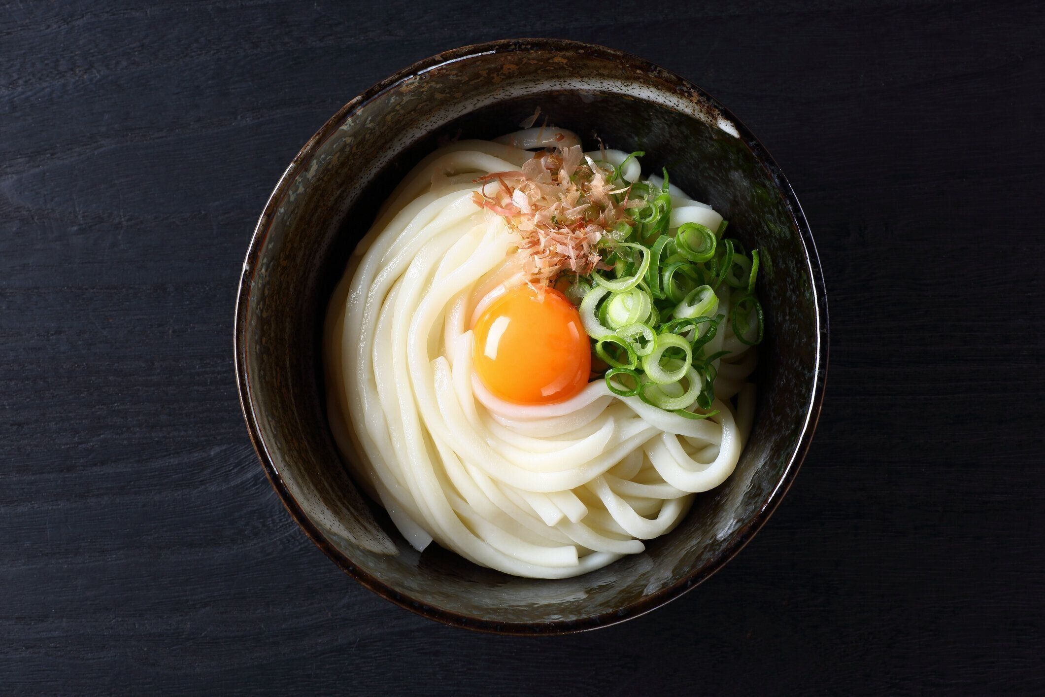 黒いテーブルに生卵を入ったうどうも