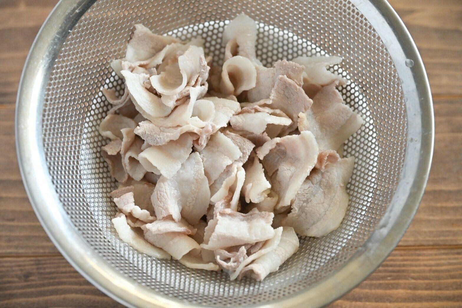 ざるに入ったゆでた豚バラ肉
