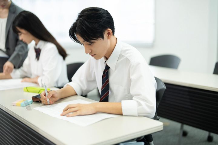 高校の制服を着たアジアのティーンエイジャーがクラスでテストを行う