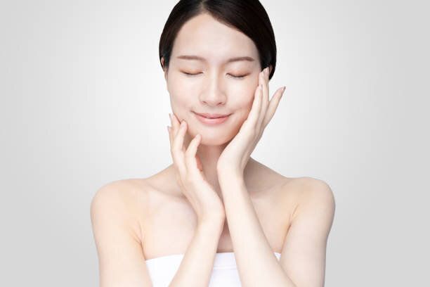 リラックスした表情で顔を触れるアジアの若い女性