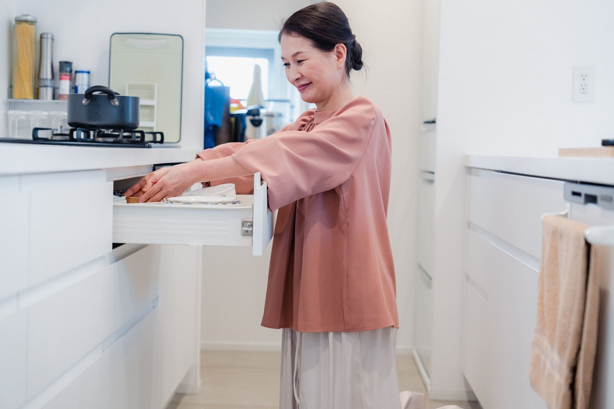 台所の収納スペースを見つけようとしている年配の女性