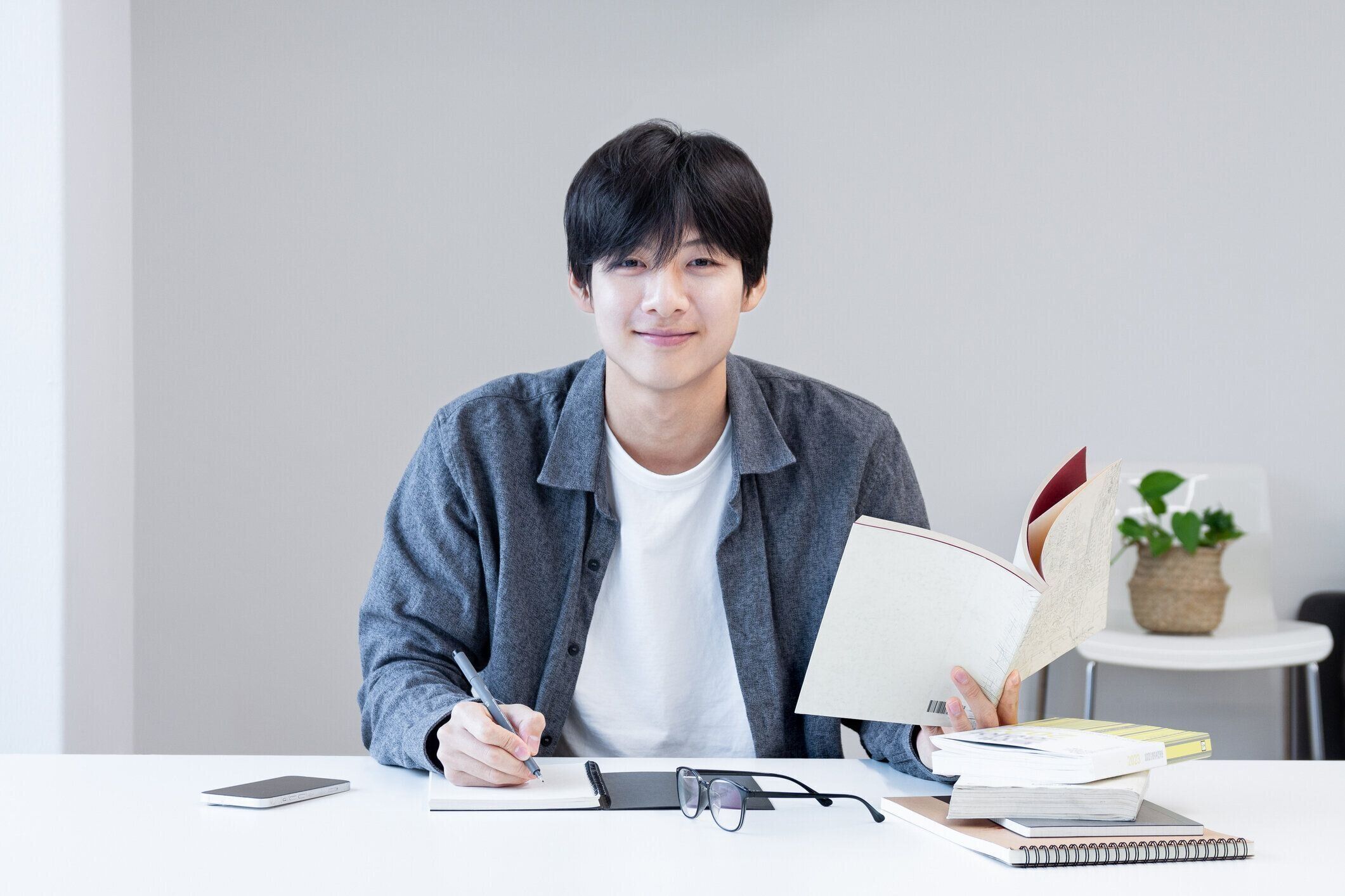 アジアの若い韓国人学生は、試験や試験の準備をする図書館で本を読みながらメモを取りながら勉強します。