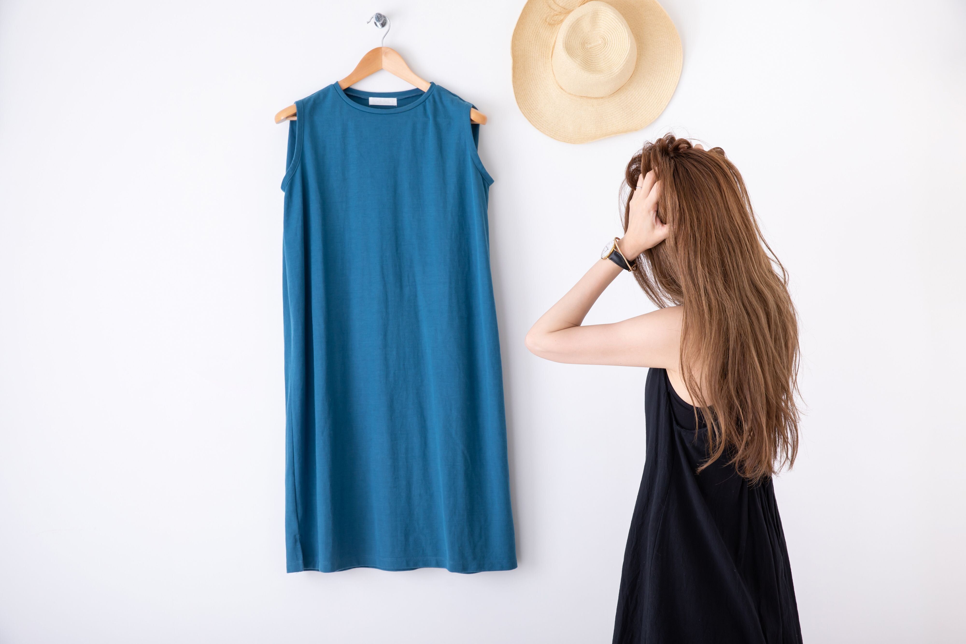 ブルーのワンピースと頭を抱える女性