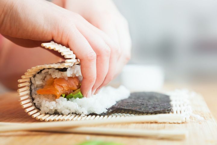 準備、ローリング寿司。サーモン、アボカド、ご飯、木製のテーブルの上の箸。