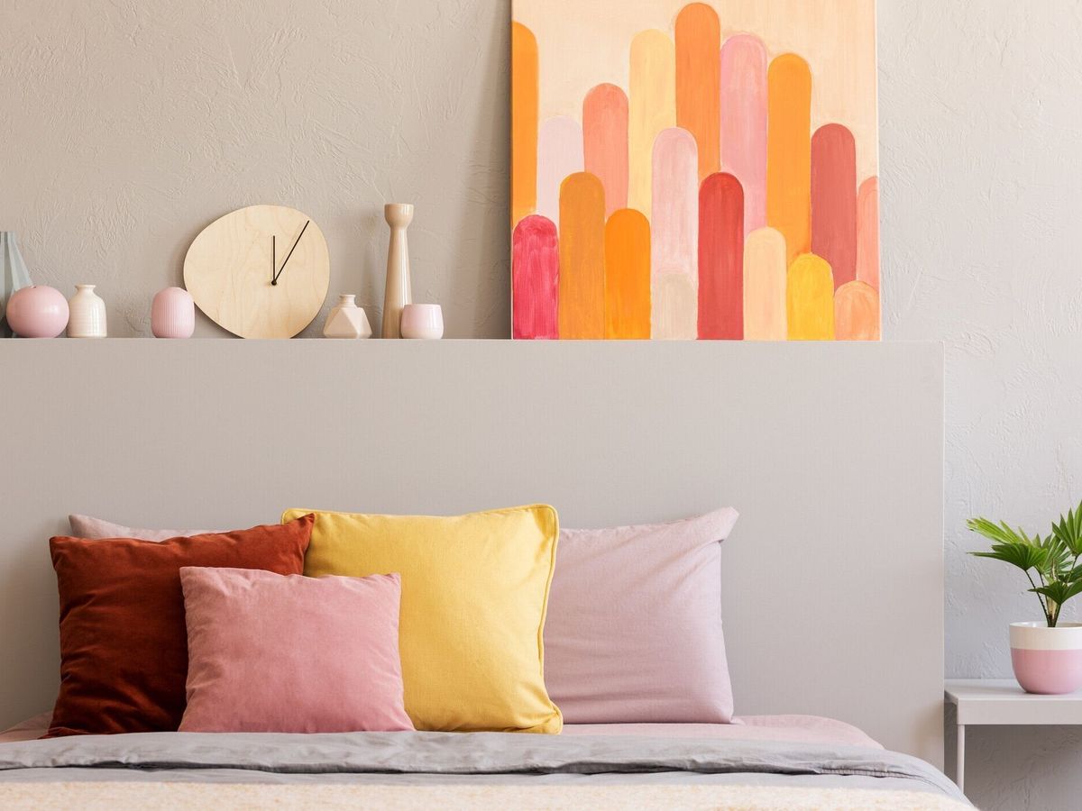 ポスターと寝癖の時計グレー寝室のインテリアでベッドの上のカラフルな枕。実際の写真