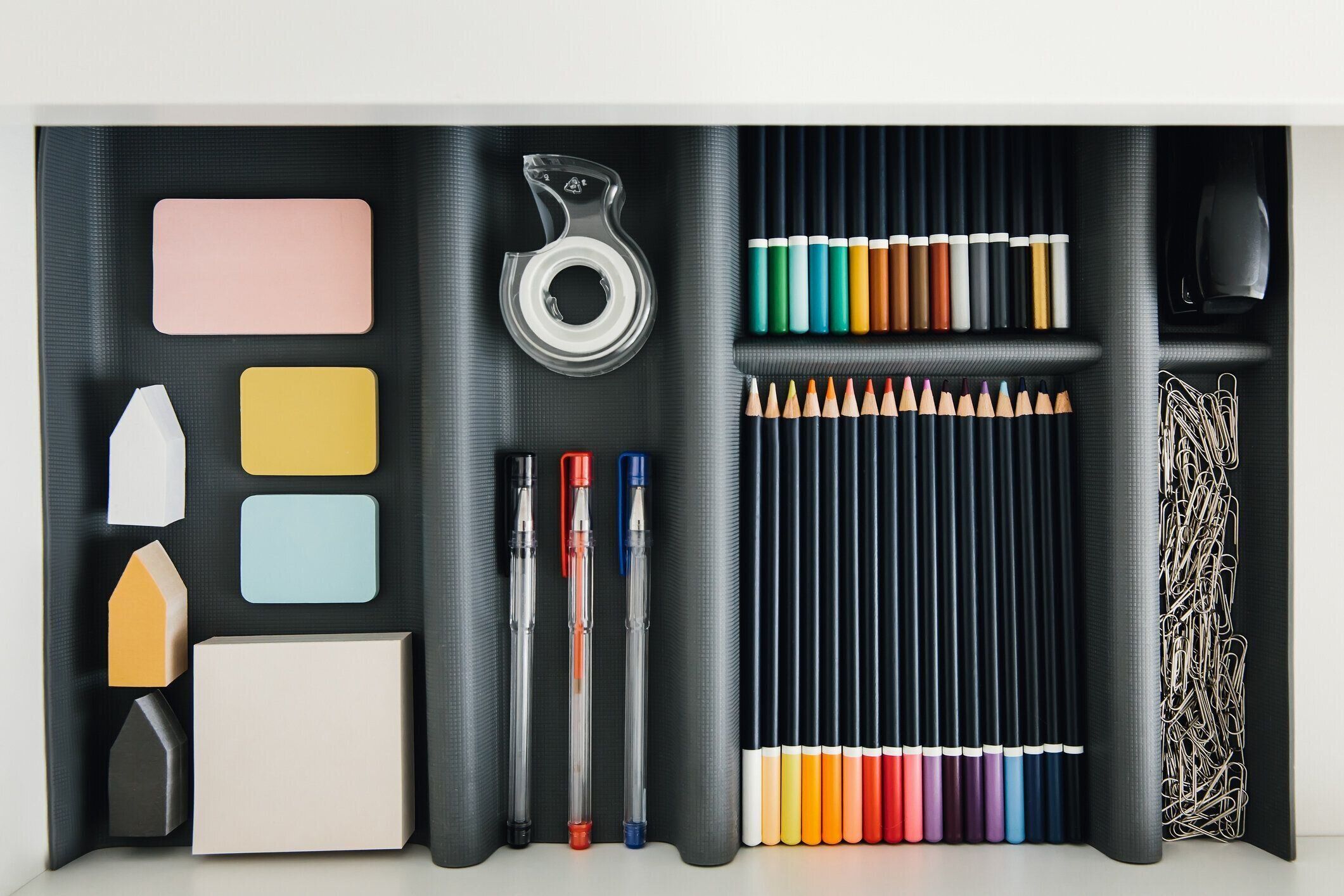 デスクトップドロワーの事務用品。ペン、鉛筆、ペーパークリップ、ノート用のカラーシートを書く。職場の秩序。学生机。