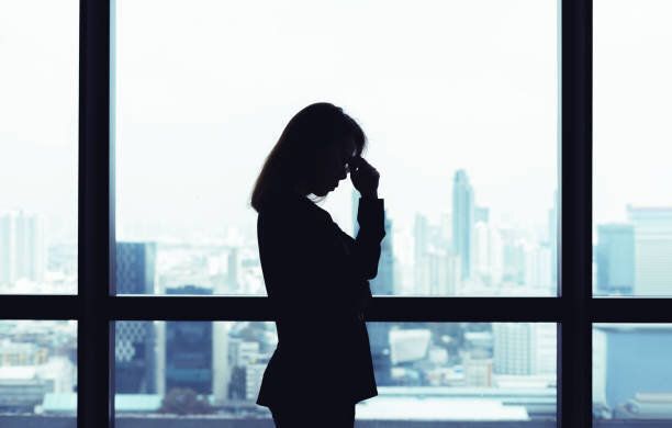 落ち込んでいるアジアのビジネス女性の窓に立って都市ビューの背景