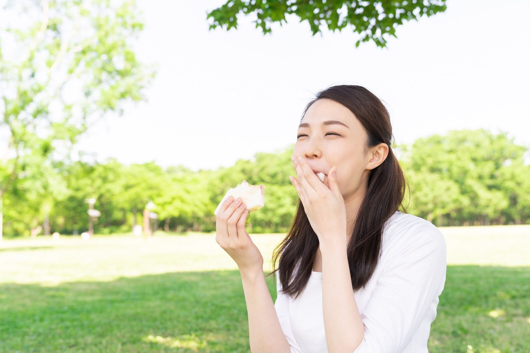 サンドイッチを食べるアジアの女性,屋外